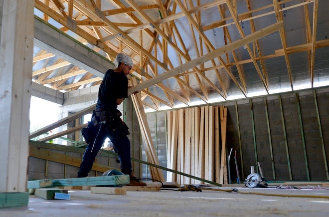 A worker hauls a beam into a home that is under construction. (File)