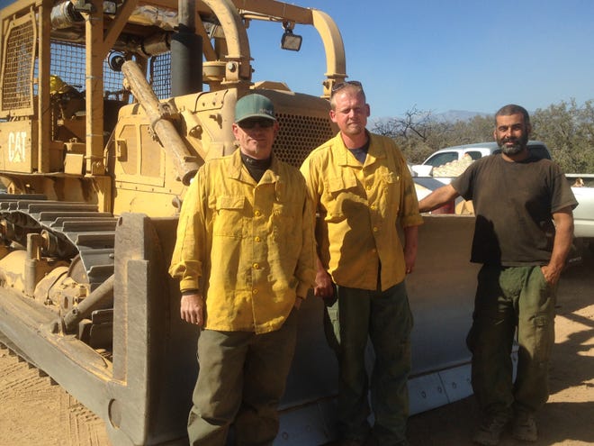 Paul Blaine, from left, Robert Wilson and Justin Cecil stand in front of a bulldozer near the area of Phelan where the crew was assigned to work containment lines for the Bluecut Fire. Cecil owns Lake Arrowhead-based Cecil Logging and was contracted to work on the Bluecut Fire earlier this week. Jose Quintero, Daily Press