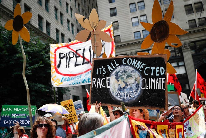 FILE - In this Sunday, July 24, 2016 file photo, climate change activists carry signs as they march during a protest in downtown in Philadelphia a day before the start of the Democratic National Convention. Matthew Nisbet, a communications professor at Northeastern University, says the split with science is most visible and strident when it comes to climate change because the nature of the global problem requires communal joint action, and "for conservatives that's especially difficult to accept." He and other experts say climate change is more about tribalism, or who we identify with politically and socially. Liberals believe in global warming, conservatives don't. (AP Photo/John Minchillo)