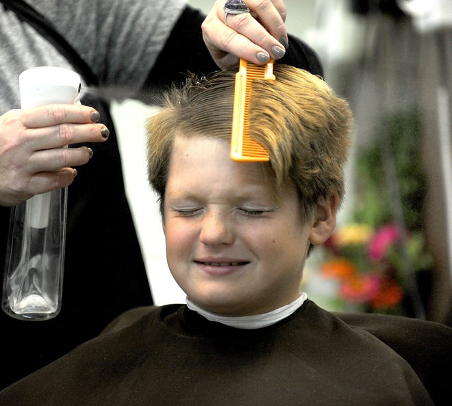 Tison Perrigo, 9, closes his eyes as DeAnna Creed cuts his hair on Tuesday at the Route B Barber Shop. The barber shop is celebrating 50 years in business at 1806 Paris Road.