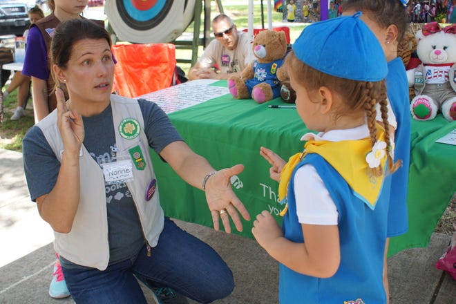 Yvonne Marchiano tries to teach the girl scout handshake to young Victoria Jones on Saturday. (Linda Charlton/correspondent)