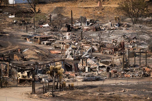 Scorched cars and trailers burned by the Blue Cut fire line a residential street in Phelan, Calif., on Friday, Aug. 19, 2016. Thousands of residents chased from their mountain and desert homes were slowly beginning to take stock of their losses as the preliminary damage assessment was released for the blaze that erupted Tuesday in drought-parched canyons 60 miles east of Los Angeles. (AP Photo/Noah Berger)