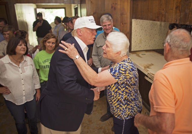 Republican presidential candidate Donald Trump, center, comforts flood victim Olive Gordan with her husband Jimmy, right, during tour of their flood damaged home in Denham Springs, La., Friday, Aug. 19, 2016. (AP Photo/Max Becherer)