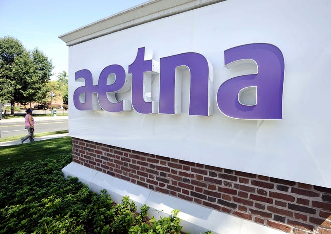 In this Tuesday, Aug. 19, 2014, file photo, a pedestrian walks past a sign for Aetna Inc., at the company headquarters in Hartford, Conn. Aetna will become the latest health insurer to chop its participation in the Affordable Care Act's public exchanges when it trims its presence to four states for 2017, from 15 this year. The nation's third-largest insurer said late Monday, Aug. 15, 2016, that a second-quarter pre-tax loss of $200 million from its individual insurance coverage helped it decide to limit exposure to the exchanges, which also have generated losses for UnitedHealth Group and Anthem, among other carriers. (AP Photo/Jessica Hill)