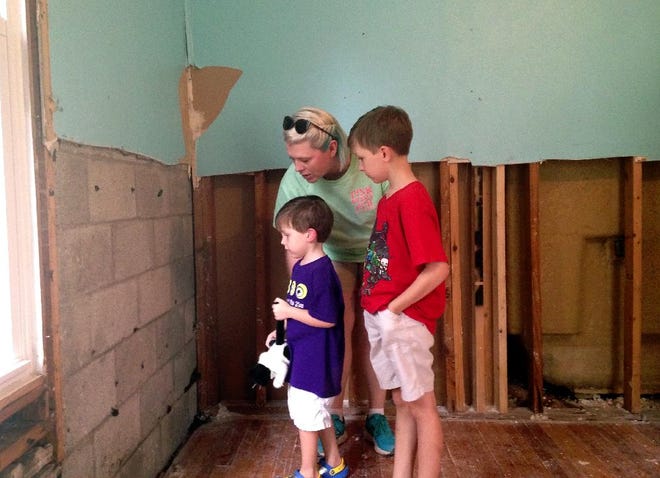 Amanda Burge looks at flood damage with two of her three children Aiden, right, and Hudson, left, at her home in Denham Springs, La., Friday, Aug. 19, 2016. "Everything is gone. School is gone. Home is gone. Church is gone," said Burge, president of the Parent Teacher Organization at Denham Springs Elementary School. (AP Photo/Michael Kunzelman)