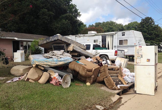 A growing pile of debris sits outside the flood-ravaged home of Carolyn and James Smith in Denham Springs, La. on Wednesday. Smith says she and four other adults will live for the time being in the travel trailer that one of her sons towed to the driveway after weekend flooding inundated the area. The Associated Press