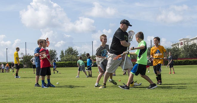Kyle Johnson teaches kids the basics at a clinic held by Lake Lacrosse at the National Training Center in Clermont on Saturday. (Paul Ryan/correspondent)