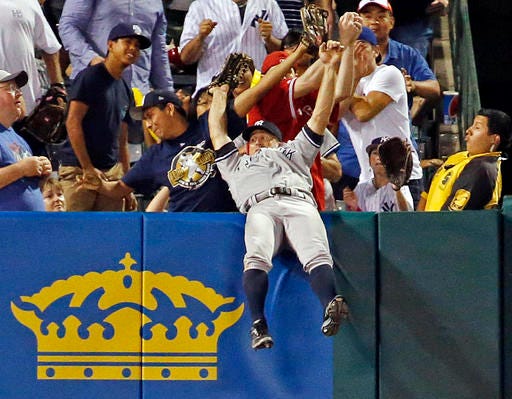 New York Yankees left fielder Brett Gardner falls backward over the wall after catching long fly ball off the Los Angeles Angels' J.J. Cron in the seventh inning of a baseball game in Anaheim, Calif., Saturday, Aug. 20, 2016. (AP Photo/Reed Saxon)