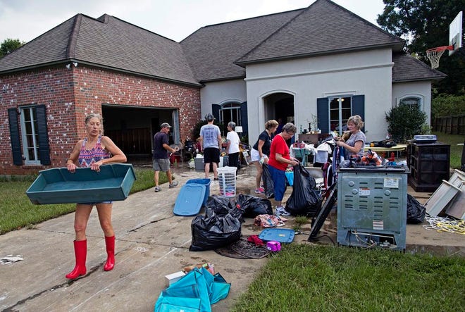 Raven Harelson, 59, left, carries a drawer to the trash heap in front the home of Sheila Siener, 58, as friends and family help to clean out the flood damaged home in St. Amant, La., Saturday, Aug. 20, 2016. Louisiana continues to dig itself out from devastating floods, with search parties going door to door looking for survivors. (AP Photo/Max Becherer)