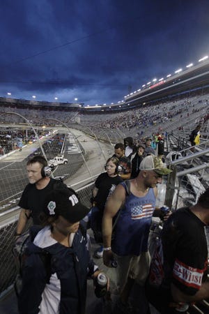 Fans make their way underneath the grandstand as severe weather delayed the start of a NASCAR Sprint Cup Series auto race, Saturday, Aug. 20, 2016, in Bristol, Tenn. (AP Photo/Wade Payne)