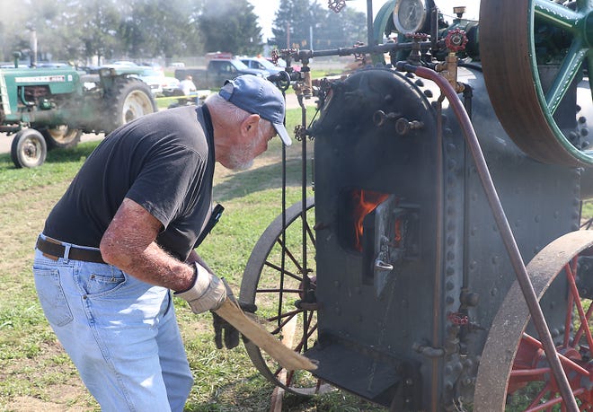 Vaughn Gordon adds wood to the fire box on the steam engine owned by John Steel during the 53rd Annual Tuscarawas Valley Pioneer Power Association Dover Steam Show at the Tuscarawas County Fairgrounds. (TimesReporter.com / Jim Cummings)