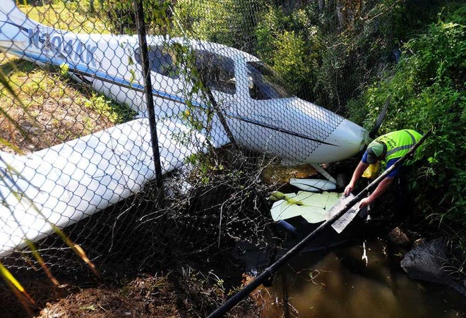 Terry.Dickson@jacksonville.com - 8/22/16 - Glynn County Public Works supervisor Robert Harrell places absorbent material into a drainage ditch at the McKinnon St. Simons Island Airport that a single engine plane skidded into Monday morning. The plane appeared to have skidded off the south end of the runway and then left into the ditch. (Florida Times-Union, Terry Dickson)