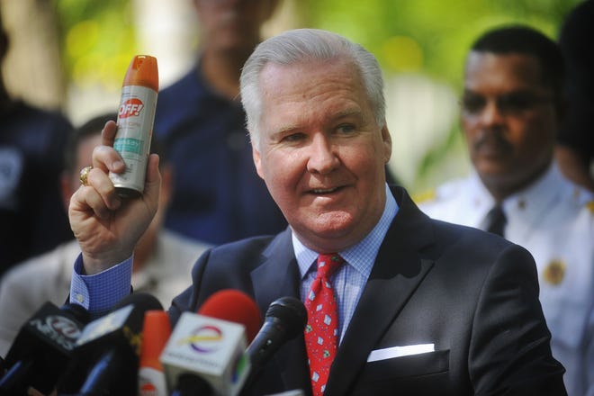 Tampa Mayor Bob Buckhorn holds up a spray can of mosquito repellent during his press conference on how to combat the Zika virus at an abandoned residence in Tampa on Monday. TAMPA BAY TIMES VIA AP / OCTAVIO JONES
