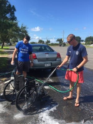 Fort Walton Beach Police Officer Adam Dee and member of the Explorers rinse off a wheelchair for a retired police officer who stopped by. Photo special to the Daily News