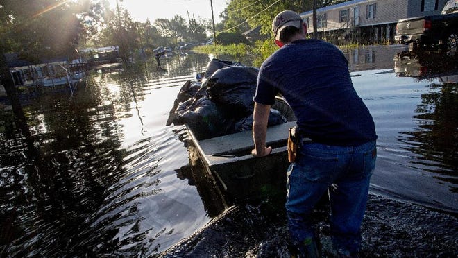 Daniel Stover, 17, moves a boat of personal belongings from a friend's home flooded home in Sorrento, La., Saturday, Aug. 20, 2016. A few Savannah businesses and residents have banded together to help the victims of the disaster through donations of household items. (AP Photo/Max Becherer)