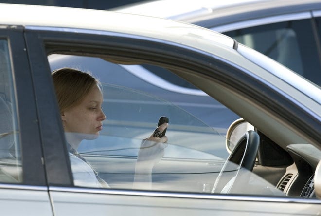 A women reads her text messages while sitting at a red light. (File)