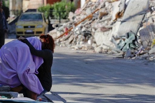 A man and woman comfort each other in front of a collapsed house, in Amatrice, Italy, Friday, Aug. 26, 2016. (AP Photo/Andrew Medichini)