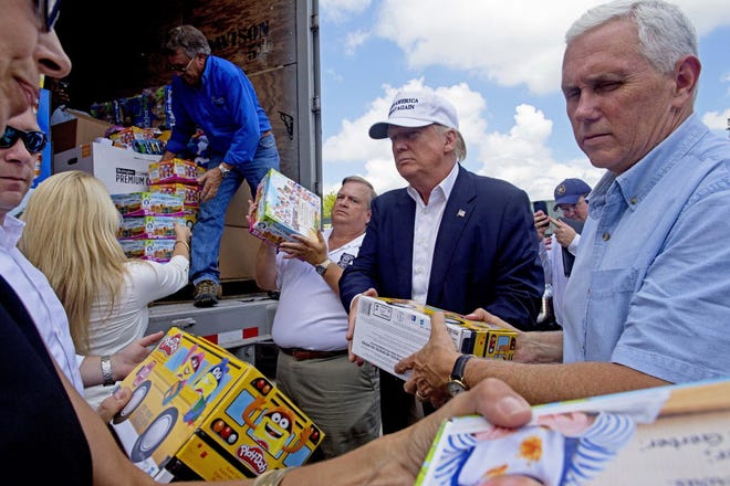 Republican presidential candidate Donald Trump and his running mate, Indiana Gov. Mike Pence, right, help to unload supplies for flood victims during a tour of the flood damaged area in Gonzales, La., Friday, Aug. 19, 2016.