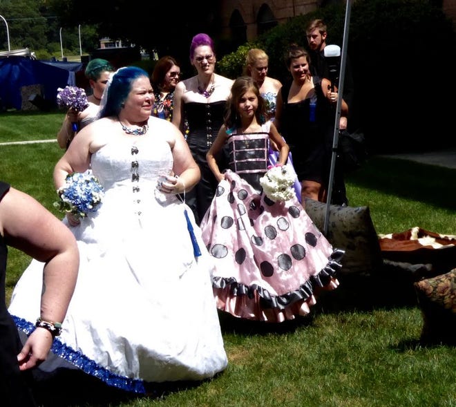 Newlyweds Kathleen Wick, in white, and Nikita Wick, with purple hair, both of Jamestown, head to have their official wedding photos taken.