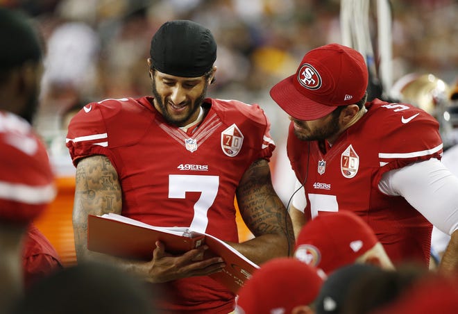 San Francisco 49ers quarterback Colin Kaepernick, left, and Christian Ponder, right, look over a playbook on the sidelines during the first half of an NFL preseason football game against the Green Bay Packers Friday in Santa Clara, Calif. Associated Press/Tony Avelar