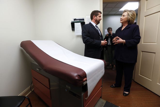 Democratic presidential candidate Hillary Clinton listens to Dr. Christopher Beckett, CEO of Williamson Health and Wellness Center during a tour an exam room of the facility in Williamson, W.Va., on May 2. With the hourglass running out for his administration, President Barack Obama's health care law is struggling in many parts of the country. Double-digit premium increases and exits by big-name insurers have caused some to wonder whether 'Obamacare' will go down as a failed experiment. AP Photo/Paul Sancya