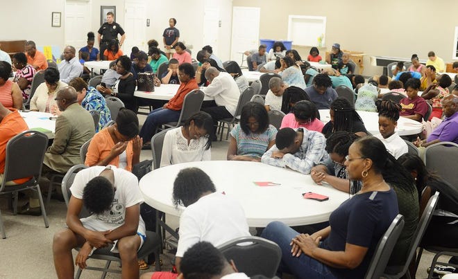 Children and adults bow their heads in prayer as they prayer for a safe and successful school year Sunday at the Back to School prayer hosted by the Kinston Teens.