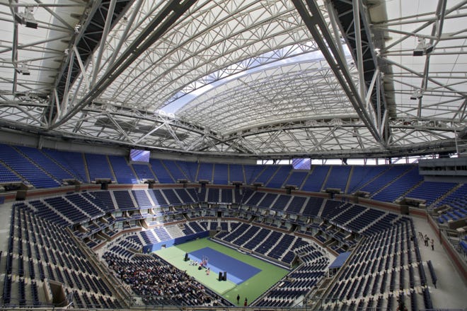 FILE - In this Aug. 2, 2016, file photo, the partially open new retractable roof allows a ribbon of light into Arthur Ashe Stadium at the Billie Jean King National Tennis Center in New York. With the stadium now covered by a retractable roof, players such as defending champ Novak Djokovic wonder how it will affect conditions when it is closed. (AP Photo/Richard Drew, File)