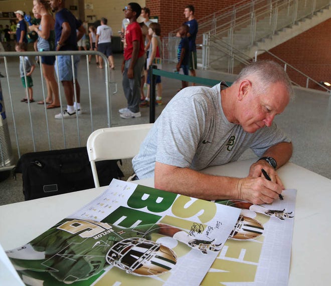 In this Aug. 6, 2016, photo, acting head coach Jim Grobe autographs a poster during the annual "Meet the Bear's," at McLane Stadium in Waco, Texas. Thousands of Baylor fans received autographs and visited with the 2016 football team. (Rod Aydelotte/Waco Tribune Herald, via AP) /Waco Tribune-Herald via AP)