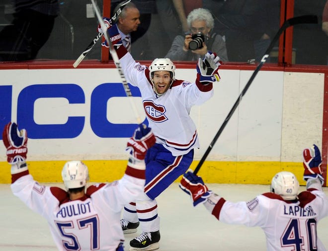 Montreal Canadiens center Dominic Moore (42) celebrates his goal with Benoit Pouliot (57) and Maxim Lapierre (40) during a playoff game against the Washington Capitals, Wednesday, April 28, 2010, in Washington.