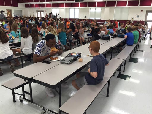 In this Tuesday, Aug, 30, 2016, photo provided by Michael Halligan, Florida State University wide receiver Travis Rudolph has lunch with Bo Paske at Montford Middle School in Tallahassee, Fla. (Michael Halligan via AP)