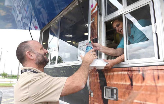 Caprock High School faculty member James Bellar gets lunch from Dorothy Delgado on Wednesday at the new AISD food truck. The Ate06 Food Truck will travel to area high schools each day to offer healthy food with a street fare spin.