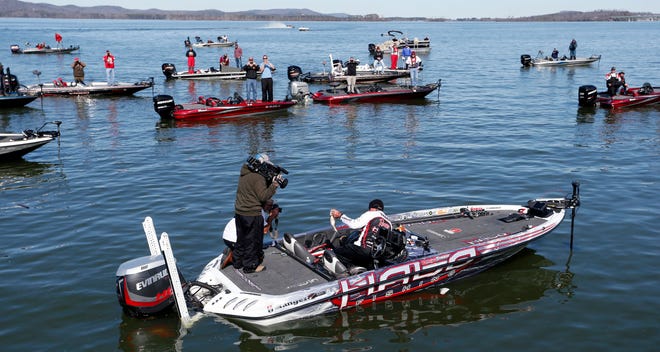 Randall Tharp of Port Saint Joe holds up a bass for spectators following him on the second day of the Bassmaster Classic in 2014 in Guntersville, Ala.