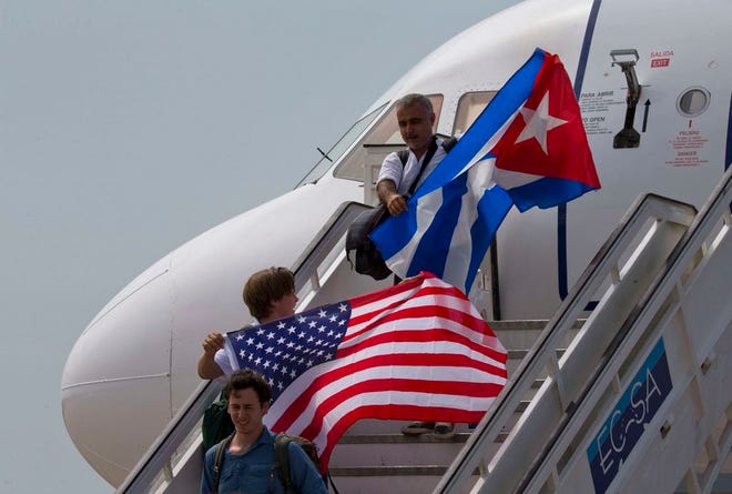 Two passengers deplane from JetBlue flight 387 waving a United States, and Cuban national flag, in Santa Clara, Cuba, Wednesday, Aug. 31, 2016. JetBlue 387, the first commercial flight between the U.S. and Cuba in more than a half century, landed in the central city of Santa Clara on Wednesday morning, re-establishing regular air service severed at the height of the Cold War. (AP Photo/Ramon Espinosa)