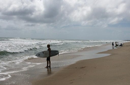 A surfer watches waves at the beach in Frisco, on the Outer Banks, N.C., Tuesday, Aug. 30, 2016. Crowds thinned Tuesday on the beaches of North Carolina's Outer Banks ahead of a tropical weather system that threatened to bring strong winds and heavy rains that could flood low-lying areas. (AP Photo/Ben Finley)