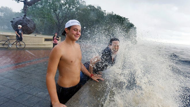 Connor Sidman and his mother Peggy Sidman get hit by a wave, as they take in the sights from the railing of Memorial Park in Jacksonville Friday.