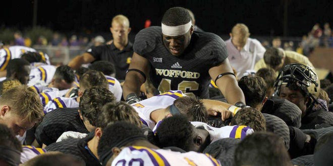 Wofford and Tennessee Tech players pray at midfield after Terriers linebacker Michael Roach collapsed on the sideline during the second half of Thursday night's game in Cookeville, Tenn.
