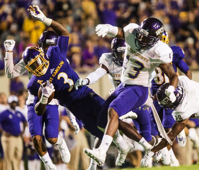 Eastern Carolina’s Anthony Scott collides with Western Carolina defenders during an NCAA college football game in Greenville Saturday. East Carolina won 52-7.