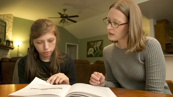 Angie De La Garza, right, helps her daughter Hailey, 13, do her homework at their home in Georgetown earlier this month.