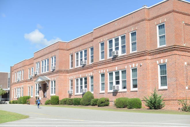 A student runs toward the front entrance of Moss Hill Elementary School on Thursday. The school is 100 years old.