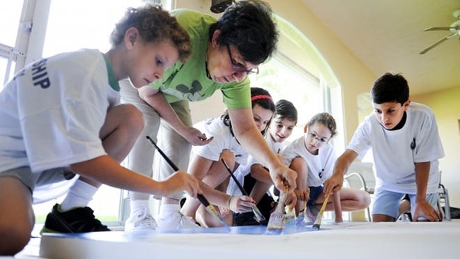 Max Friedman, 8, Debbie Simon, a resident of a group home for people with learning disabilities, Lauren Schram, 11, Sam Friedman, Rose Friedman, 9, and Jonathan Schram, 10 paint a seascape during a Fellowship Friday event sponsored by Palm Beach Fellowship of Christians & Jews. Volunteers visited the group home to help create a painting under the guidance of Palm Beach Artist Sandra Thompson.