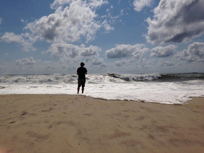 A beachgoer stands at the edge of the water, Sunday, Sept. 4, 2016, in Bridgehampton, N.Y., on the southeastern shore of Long Island, where the effects of storm system Hermine could be seen in the rough surf and a ban on swimming. Hermine spun away from the U.S. East Coast on Sunday, removing the threat of heavy rain but maintaining enough power to churn dangerous waves and currents and keep beaches off-limits to disappointed swimmers and surfers during the holiday weekend. (AP Photo/Jennifer Peltz)