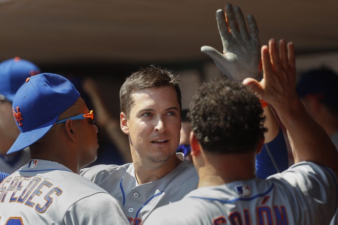 Mets' Kelly Johnson, center, celebrates in the dugout after hitting a solo home run against the Reds in the fifth inning. The Associated Press