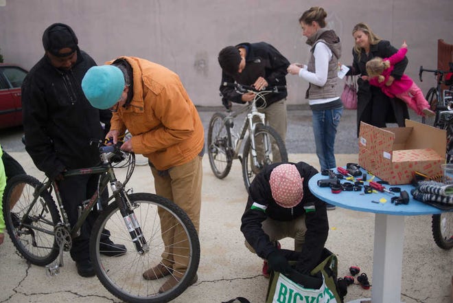 People install bicycle lights at a free event organized by BikeAthens, Complete Streets Prince Avenue and the Downtown Athens Business Association on Thursday, Nov. 13, 2014, in Athens, Ga. (Staff File Photo)