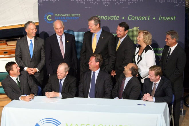 Officials of the Commonwealth, including Gov. Charlie Baker, back third from left, as well as the City of New Bedford, including Mayor Jon Mitchell, back left standing, witness a letter of intent signed by investors of offshore wind companies.