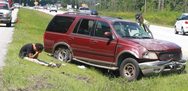 Driver Corey Davis Pritchett Jr., 25, of Newport, left, holds his head in his hands as he sits next to his crumpled Ford Expedition as N.C. Highway Patrol Trooper D.M. Davis investigates the wreck Tuesday afternoon one mile east of Havelock on U.S. 70. Pritchett suffered minor injuries in the wreck, but two hours later, was found unconscious in the bathroom of the nearby Food Lion in Havelock as a result of an apparent drug overdose, according to police.