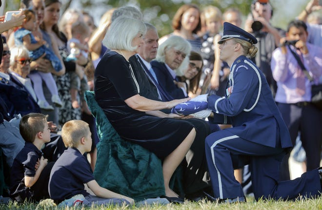Air Force Capt. Jennifer Lee, right, kneels Wednesday as she presents an American flag to Terry Harmon, center seated, daughter of World War II pilot Elaine Danforth Harmon, during burial services at Arlington National Cemetery in Arlington, Va. Associated Press/Pablo Martinez Monsivais