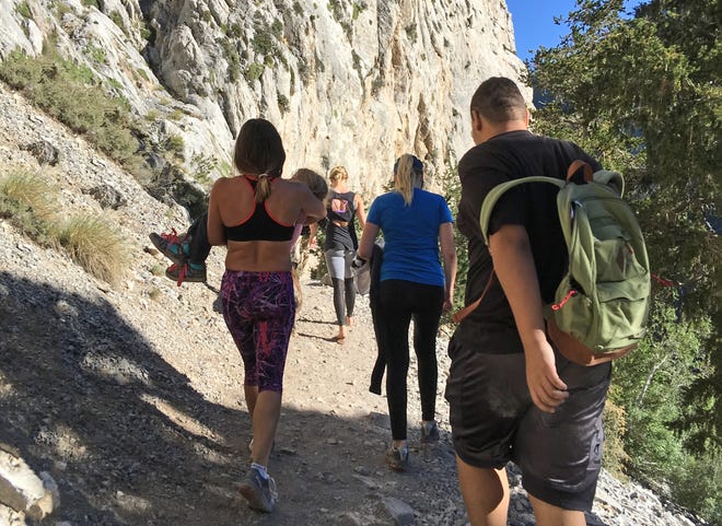 In this Sept. 4, 2016, photo provided by Myra Fukuno, former mixed martial arts Ultimate Fighting Championship women's bantamweight champion Miesha Tate, left, carries a little girl with a broken arm down Mount Charleston near Las Vegas. Tate says she's inspired by the tough little girl who broke her arm while hiking near Las Vegas. Tate posted on Facebook that she encountered the 6-year-old Sunday, on the popular Mary Jane Falls trail of Mount Charleston, about 40 miles northwest of Las Vegas. (Myra Fukuno via AP)