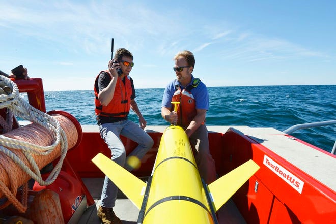 In this Sept. 2, 2016 photo, Woods Hole Oceanographic Institution engineers Patrick Deane, left, and Sean Whelan prepare to release a Slocum glider into the waters south of Martha's Vineyard, Mass. to monitor anticipated changes in the ocean during the passage of tropical storm Hermine. The underwater drones, or gliders as they are known, collect data that scientists say will help them better understand what sustains and strengthens hurricanes and tropical storms.