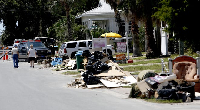 A couple walks past piles of trash from the inside of flooded homes along 1st Street on Wednesday, Sept. 7, 2016 in Cedar Key, FL. Many homes and businesses were flooded by the storm surge from Hurricane Hermine. Matt Stamey/Gainesville Sun