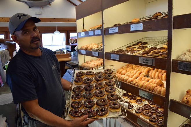Ruben Alvarz, who has been a server at the Donut Hole for 26 years, holds a tray of chocolate icing donuts. The Donut Hole has been a Destin sta-ple for almost 40 years.